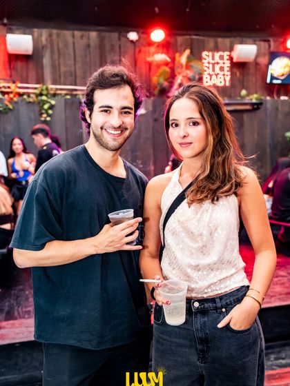 Una pareja brinda mirando a la cámara, con la luz roja del salón detrás.