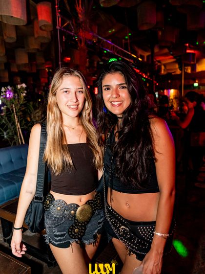 Dos amigas posan juntas con la luz azulada de la pista detrás.