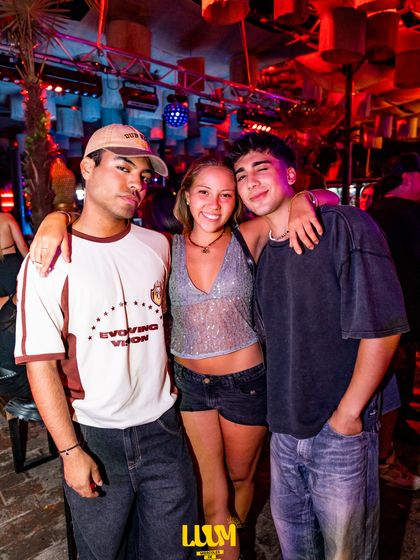 Un grupo de cuatro amigos posa abrazado en medio de la fiesta, con luz violeta.
